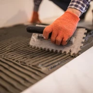 Image d'une personne qui prépare la pose d'une dalle de carrelage.